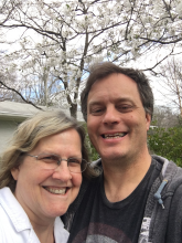A woman and a man standing in front of branches with cherry blossoms