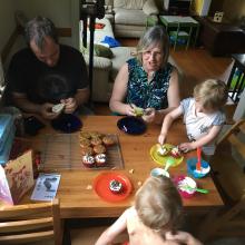 Two children and two adults at a table eating cupcakes